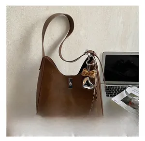 Detail of dark brown leather hobo bag with silver heart charm and leopard bow