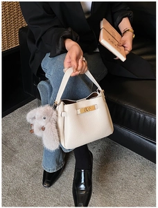 Detail of cream lychee leather bucket bag with gold lock and plush rabbit charm