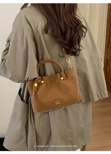 Detail of retro brown suede bucket bag featuring circular handles and COIN 2DN logo