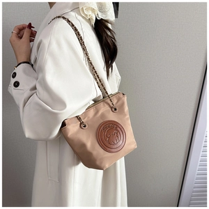 Detail of beige nylon shoulder bag featuring leather cartoon dog patch and chain strap