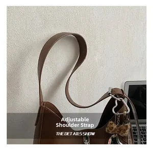 Detail of adjustable strap with silver buckle and leopard plush heart charm on brown bag