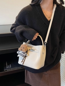 Chic beige lychee leather bucket bag with top handle and cute puppy charm accessory