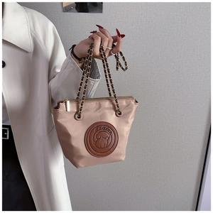 Detail of beige nylon bag with puppy patch and leather chain strap shown by a model
