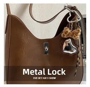 Detail of brown hobo bag featuring silver twist lock and leopard bow heart charm