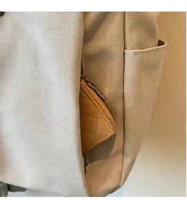 Vue détaillée d'un sac en toile avec une poche zippée latérale cachée et un petit porte-monnaie
