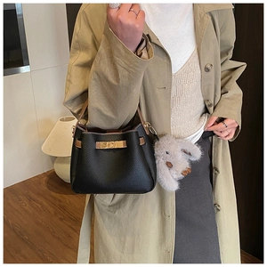 Close-up of black pebble leather bucket bag with gold lock and plush bunny charm