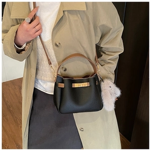 Detail of black pebbled leather bucket bag with gold lock and plush bunny charm