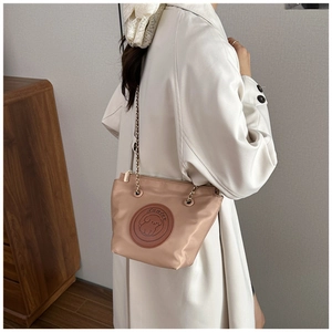 Détail du sac seau abricot avec son écusson en cuir de chien et bandoulière dorée