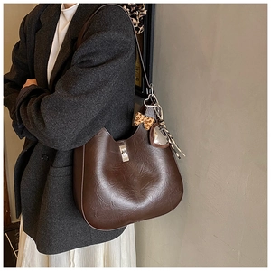 Close-up of a large brown faux leather tote bag featuring a leopard bow and silver clasp