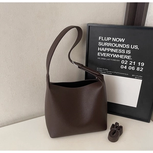 Detail of dark brown lychee leather tote bag with adjustable shoulder strap and texture