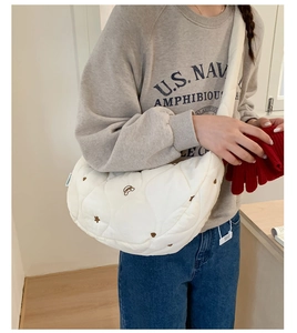 Détail latéral du sac demi-lune blanc matelassé avec broderie cœur et étoile