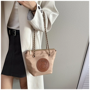 Détail du sac cabas beige en nylon avec écusson chien en cuir marron et chaîne dorée