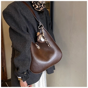 Detail of coffee brown glossy faux leather shoulder bag with a heart mirror pendant