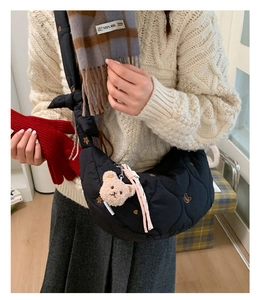 Détail du sac croissant matelassé noir avec broderie dorée et breloque ours en peluche