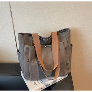 Detail of dark grey canvas tote bag with multiple pockets and brown woven handles