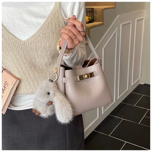 Detail of lavender bucket bag with lychee texture and plush rabbit keychain accessory