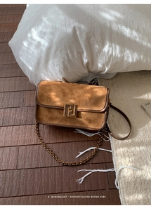 Détail du sac à main rétro en daim marron avec fermoir bronze et bandoulière chaîne