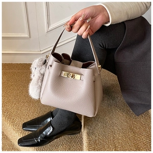 Detail of lychee pattern leather bucket bag with gold twist lock and plush rabbit charm