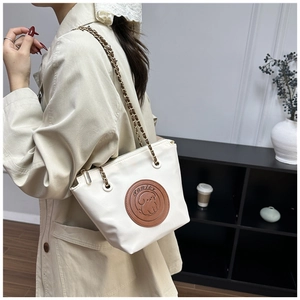 Detail view of cream bucket bag showing woven chain strap and cartoon puppy patch