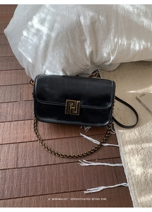 Détail d'un sac à bandoulière rétro noir avec fermoir doré sur cuir huilé et ciré
