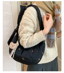 Détail du sac bandoulière matelassé noir avec broderie étoile et breloque ours brun