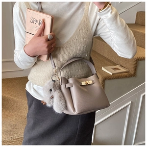 Detail view of taupe bucket bag with lychee texture and cute rabbit charm accessory