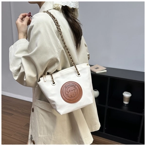 Detail of Pawlee cream chain shoulder bag showing brown leather patch and woven strap