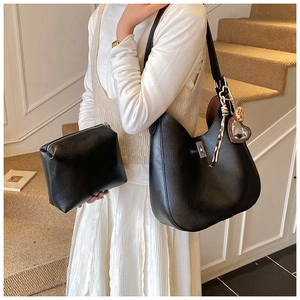 Detail of black pebbled leather bucket bag set with silver twist lock and heart charm