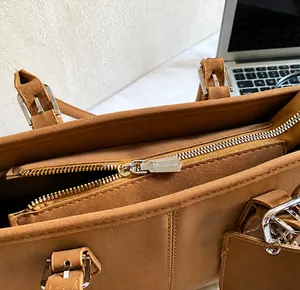 Close-up of caramel leather tote with silver zipper and adjustable buckle details
