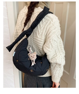 Détail du sac hobo noir matelassé avec bandoulière nouée et breloque ourson