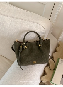 Macro detail of dark green matte leather handbag with metal ball and tassel charm