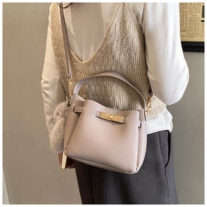 Detailed side view of lilac lychee leather bucket bag with fur ball and gold lock