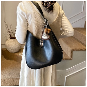 Detail shot of black hobo bag with silver twist lock and leopard bow on white skirt