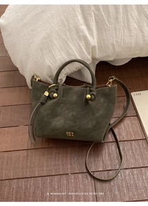 Close-up of deep green leather bucket bag with gold hardware on wooden floor