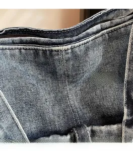 Detail of high-quality washed denim fabric with white double stitching and belt loops