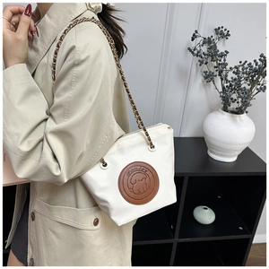 Détail du sac blanc avec patch en cuir chiot de dessin animé et bandoulière en chaîne
