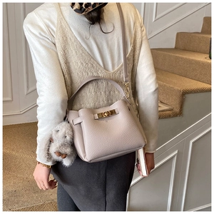 Close-up of beige lychee grain leather bucket bag with gold clasp and bunny charm
