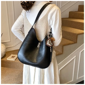 Detail of black faux leather half-moon tote with silver metal twist lock and leopard charm