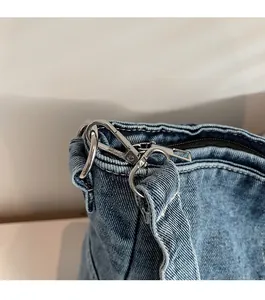 Detailed close-up of shiny silver metal hook and premium denim fabric on crossbody bag