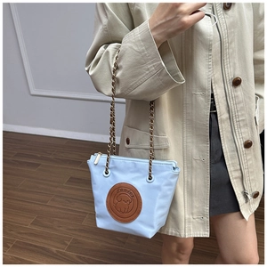 Detail of light blue bucket bag with cartoon puppy embossing and chain strap