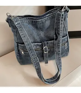 Close-up of dark blue denim tote bag featuring dual front zipper pockets and adjustable strap