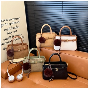 Detail of woven texture bucket bags with fur ball charms in five versatile colors