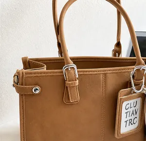 Close-up of brown leather tote bag with adjustable handles and side buckle detail