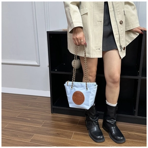 Detail of blue nylon bucket bag with golden chain strap and a leather dog patch