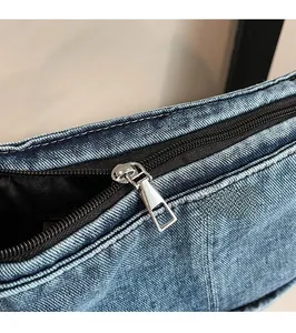 Close-up of smooth silver metal zipper and fine stitching on blue denim tote bag