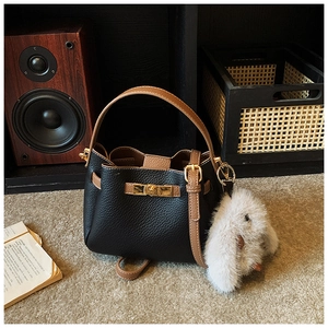 Close-up of pebble leather bucket bag with metal buckle and rabbit plush charm