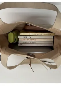 Top view of large beige canvas tote bag showing interior space with laptop and books