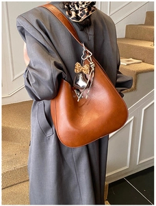Brown leather tote bag with heart pendant and leopard print bow on a model shoulder