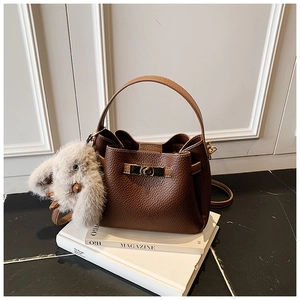 Detail of dark brown pebble leather bucket bag with gold twist lock and bunny charm