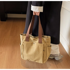 Detail of khaki canvas tote bag with brown straps and functional snap front pocket